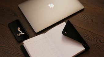 Flat lay of a laptop, smartphone, notepad, and icons representing business tools