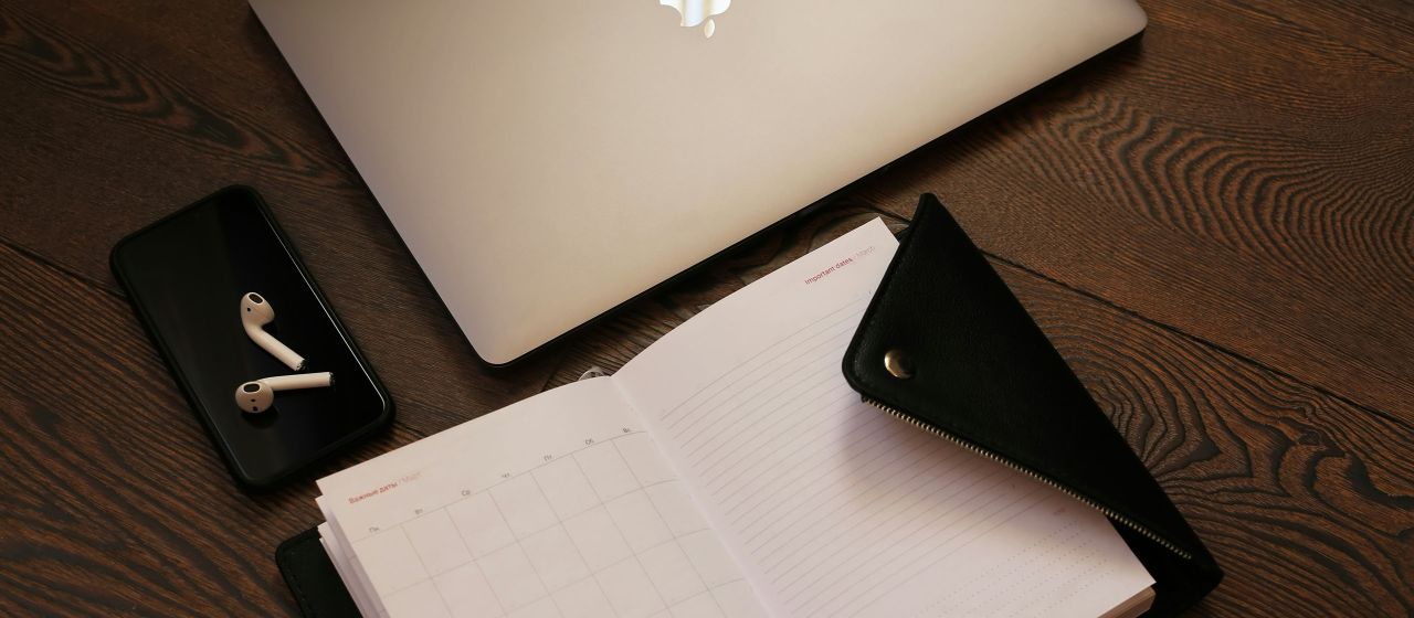 Flat lay of a laptop, smartphone, notepad, and icons representing business tools