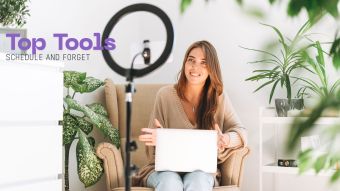 Influencer using a laptop to schedule social media posts with a ring light and phone tripod nearby.