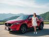 2026 Mazda CX-5 in red parked at a scenic mountain viewpoint with a young Asian woman in a white dress standing beside it